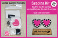 Beading kit bag of beads and supplies beside the finished pink heart with flowers earrings it makes, with a ruler