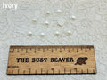 Ten 10mm ivory pearl-look resin half round cabochons (cabs) beside a ruler