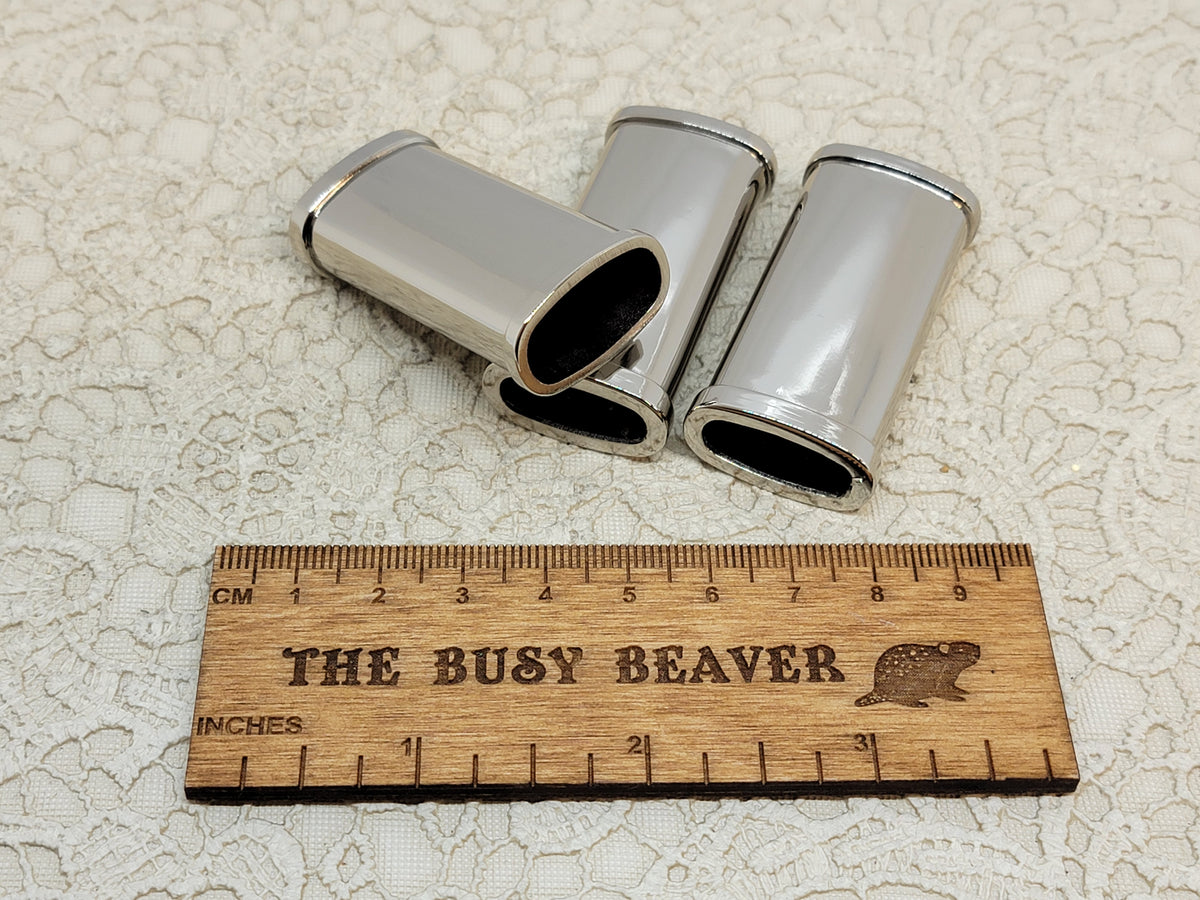 Three blank silver J5 lighter cases with ridged edges beside a ruler