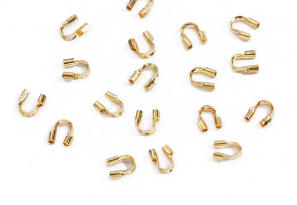 Scattered KC Gold horseshoe-shaped wire guards on a white background