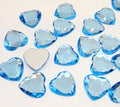 Pile of 20mm faceted light blue resin heart gem cabochons (cabs), one flipped to show the flat back