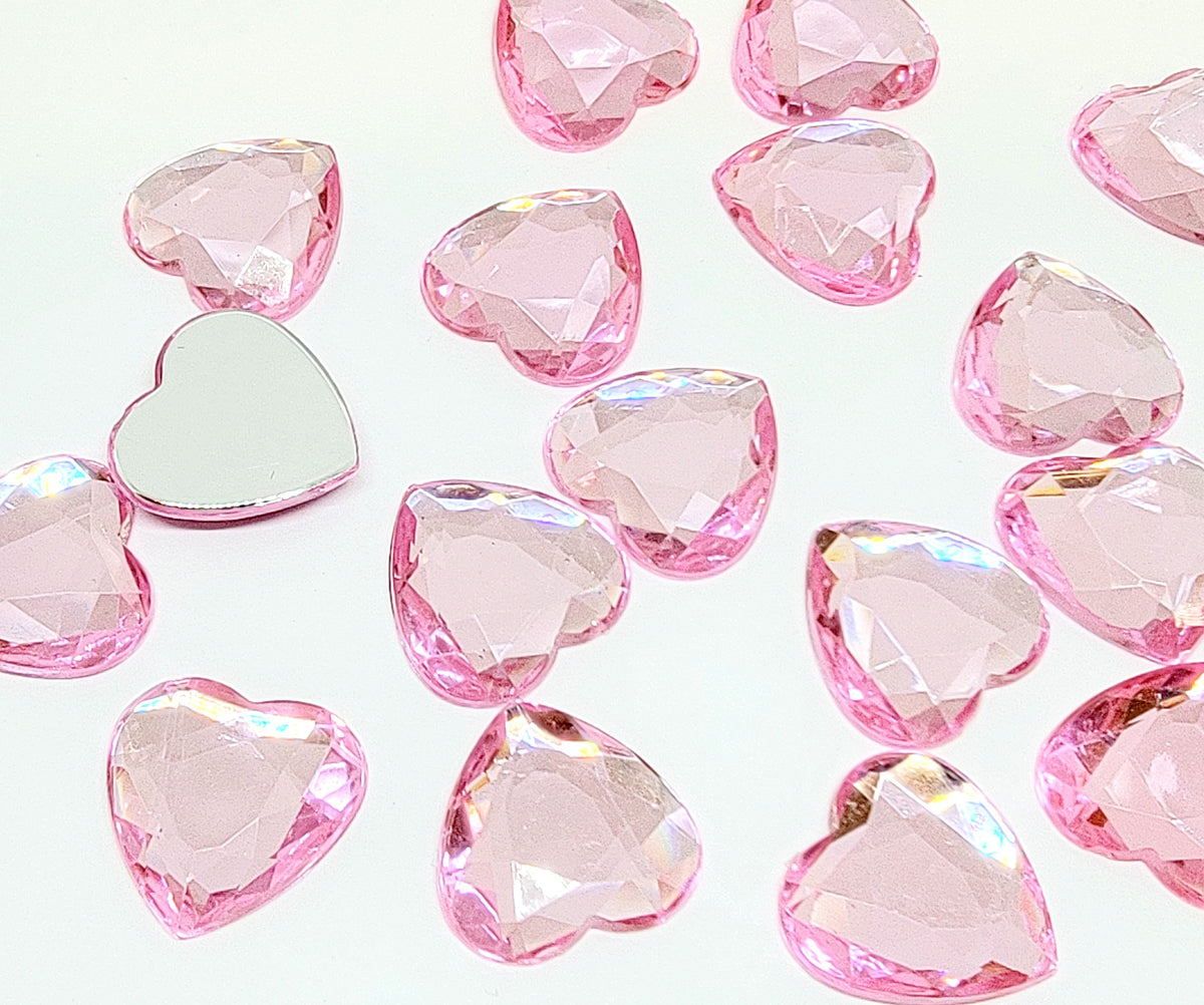 Pile of 20mm faceted light pink resin heart gem cabochons (cabs), one flipped to show the flat back