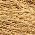 Close-up of strung Preciosa 13/0 true cut charlotte beads in metallic gold