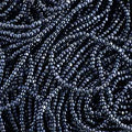 Close-up of strung Preciosa 13/0 true cut charlotte beads in metallic gunmetal