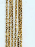 Hanging strands of 2mm gold stainless steel link chain against a white background