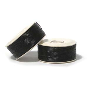 Two large black Nymo thread bobbins, one on its side on white