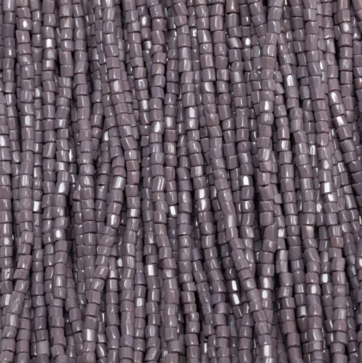 Close-up of strung Preciosa 9/0 three-cut glass seed beads in opaque dark mauve