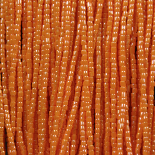 Close-up of strung Preciosa 9/0 three-cut glass seed beads in opaque light orange with a luster finish
