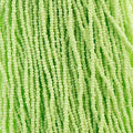 Close-up of strung Preciosa 13/0 true cut charlotte beads in opaque pale green