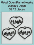 Three black 20 x 21mm open heart charms with flame cut-outs on a labelled product card