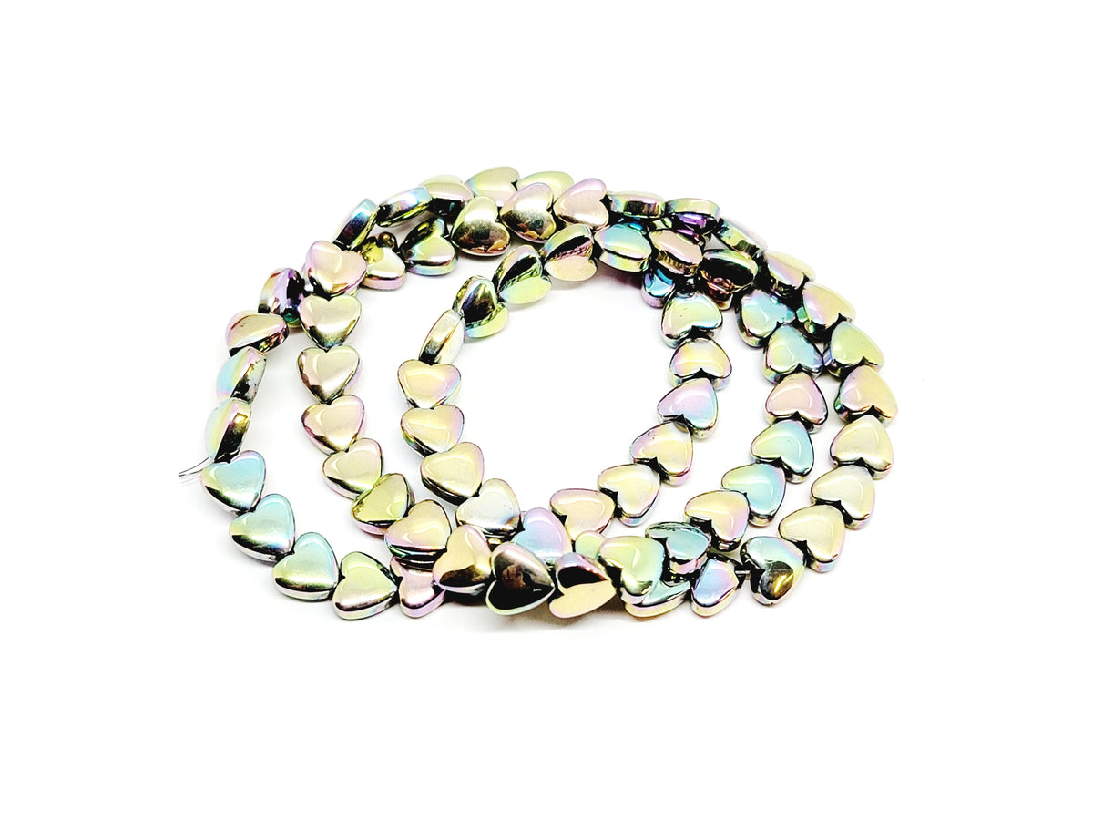 Strand of 6mm pastel rainbow hematite heart beads coiled on a white background