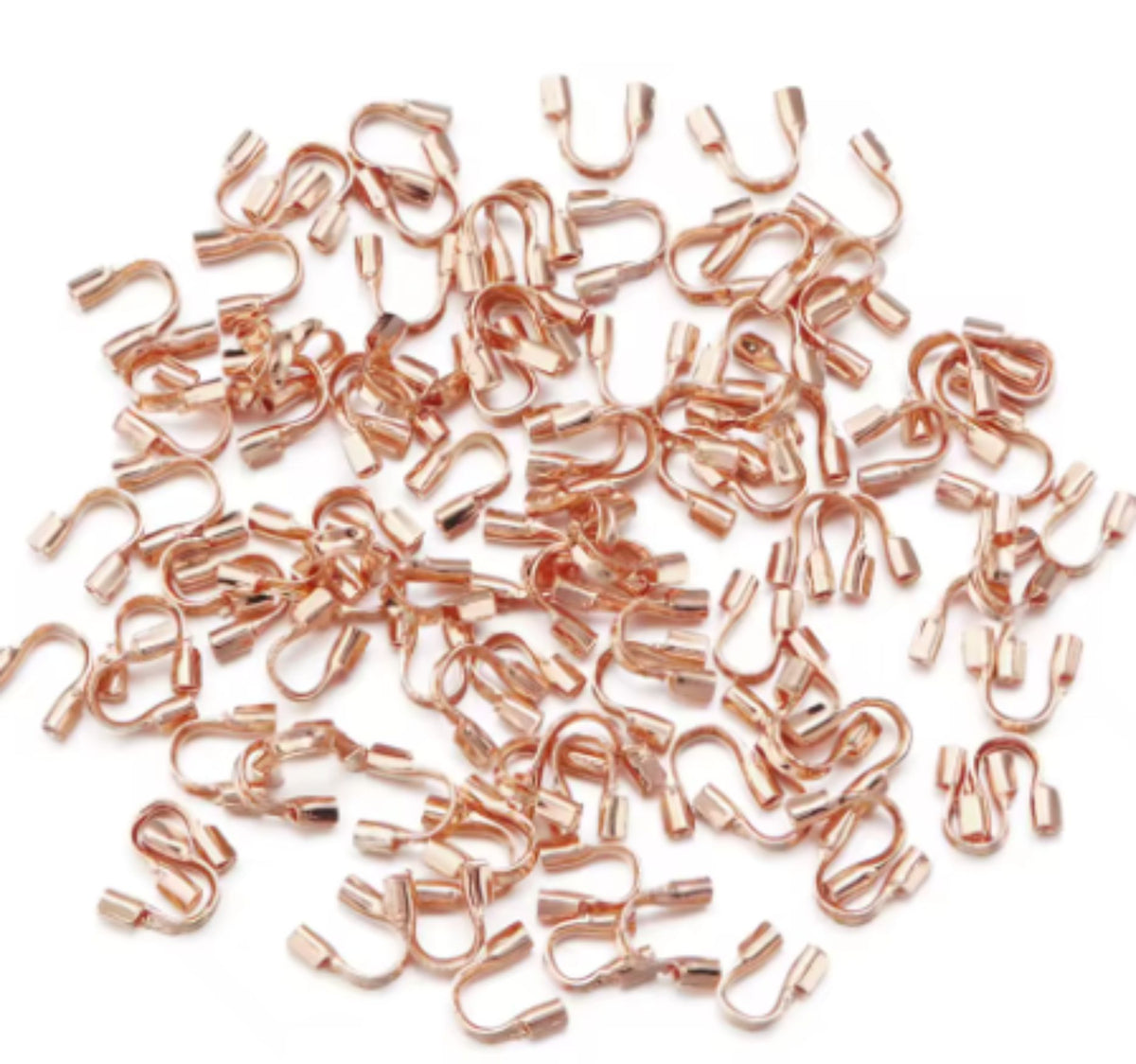 Scattered rose gold horseshoe-shaped wire guards on a white background