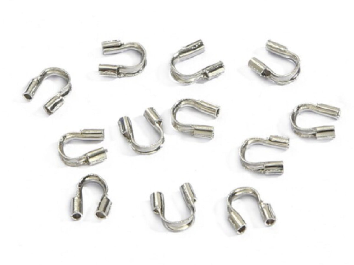 Scattered rhodium horseshoe-shaped wire guards on a white background