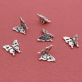Silver-tone 14 x 15mm butterfly charms scattered on a red background