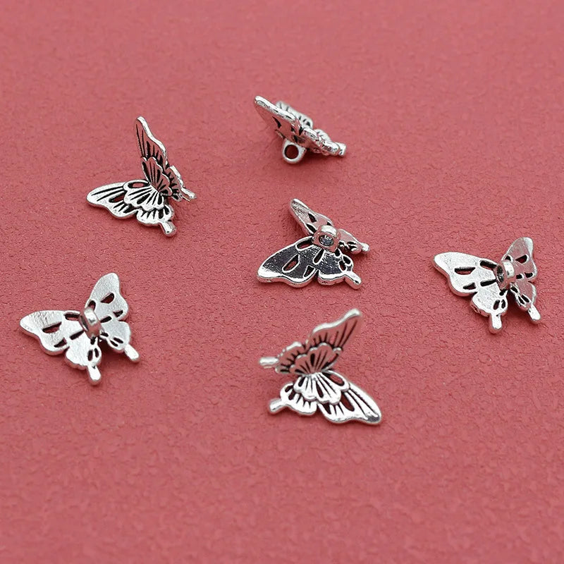 Silver-tone 14 x 15mm butterfly charms scattered on a red background