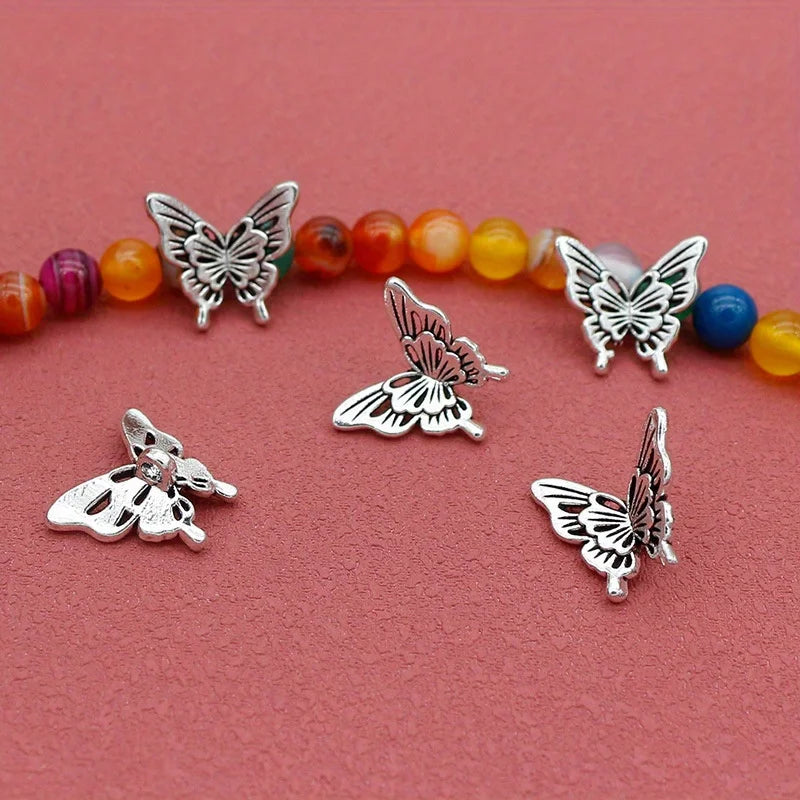 Silver-tone butterfly charms beside a strand of colourful beads on a red background