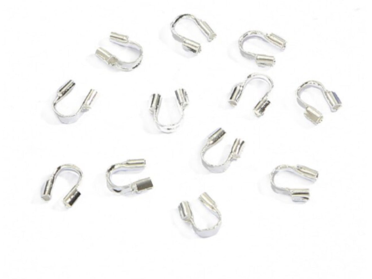 Scattered silver horseshoe-shaped wire guards on a white background