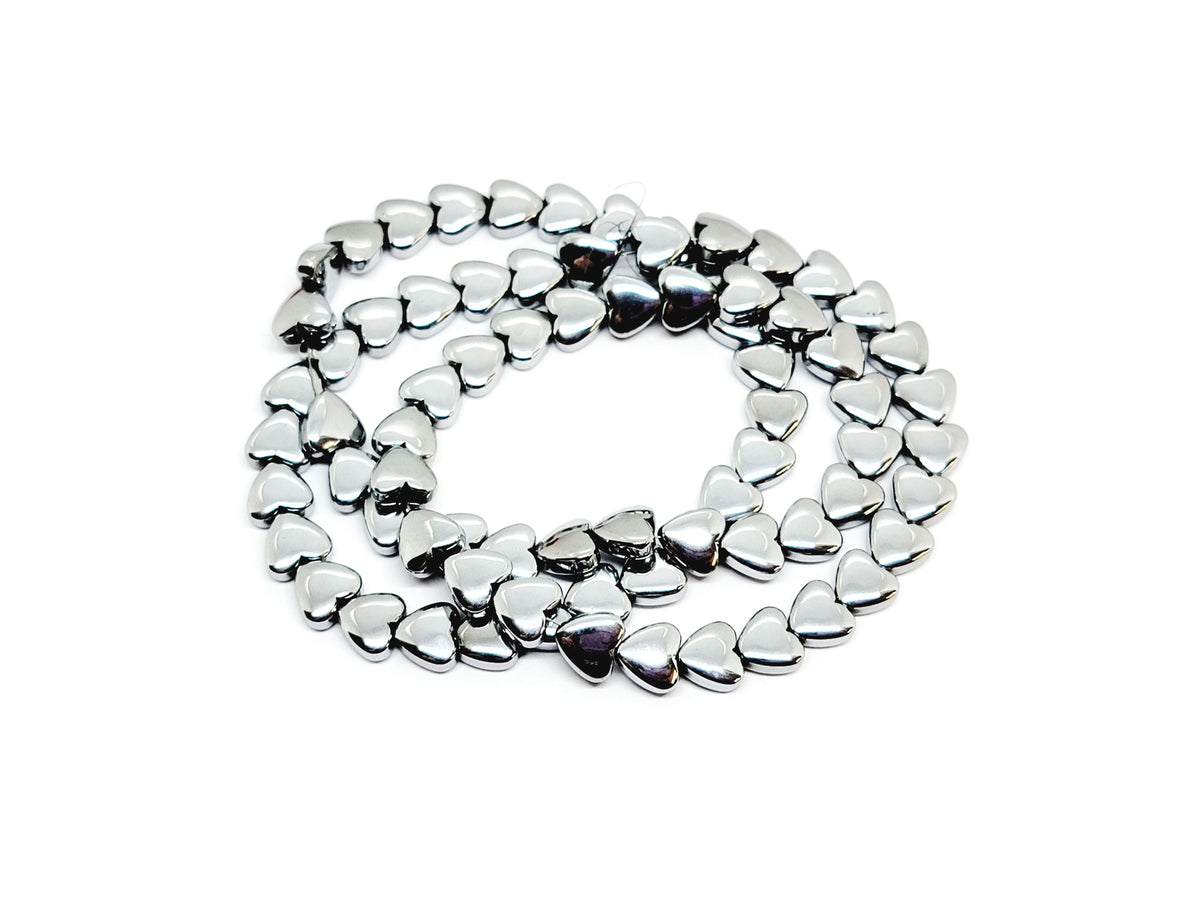 Strand of 6mm silver hematite heart beads coiled on a white background