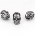 Two antique silver-tone skull beads with large holes on a white background