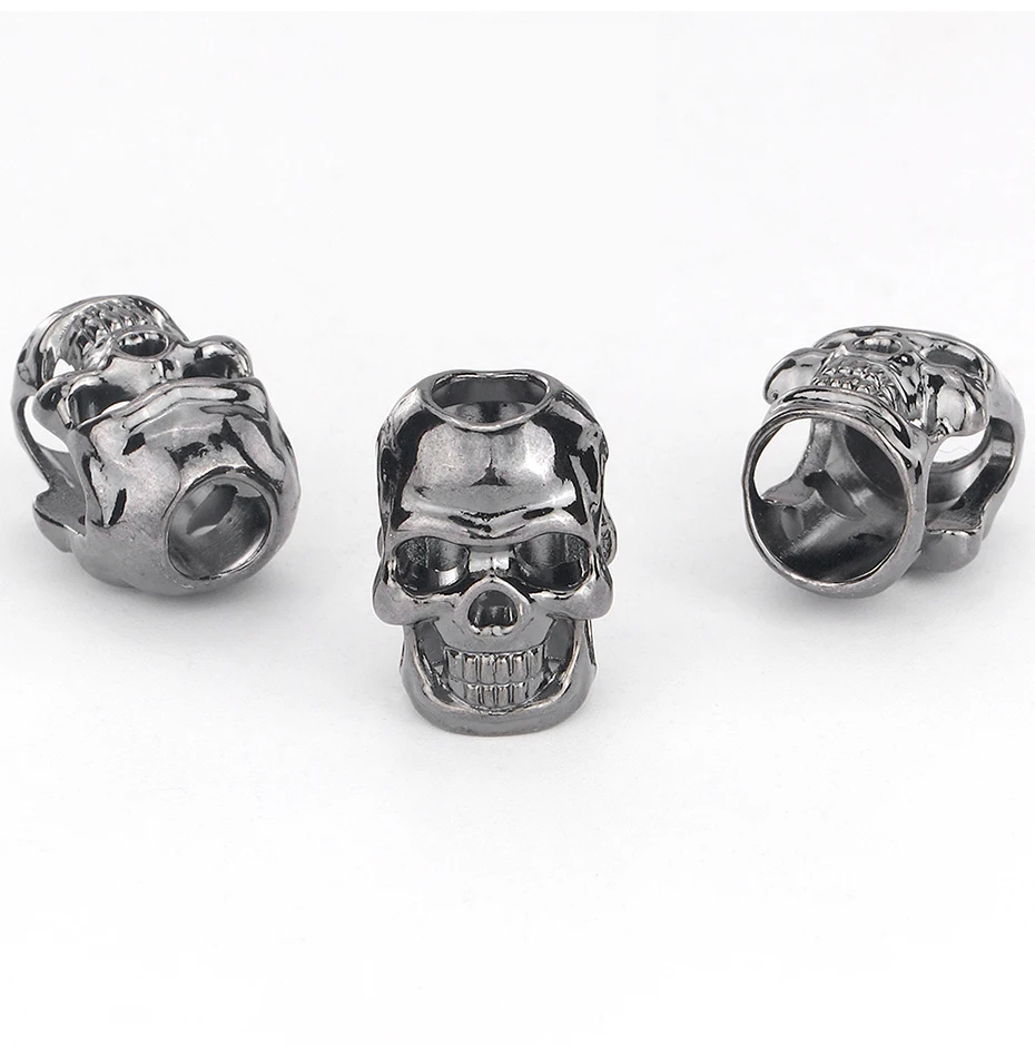 Two antique silver-tone skull beads with large holes on a white background