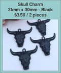Four black 21 x 30mm steer skull charms with horns on a labelled product card