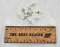 Ten silver-tone 7 x 15mm cross charms beside a ruler for scale