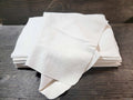 Folded white soft sheepskin leather squares stacked on a wooden surface