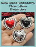 Spiked 29 x 42mm heart charms in red, black and silver, held in a hand