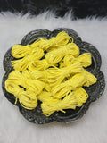 Bundles of 2.7mm sunshine yellow suede leather lacing coiled on a dark scalloped dish