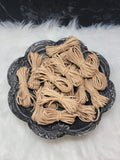 Bundles of 2.7mm tan suede leather lacing coiled on a dark scalloped dish