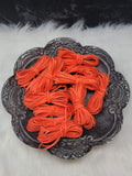 Bundles of 2.7mm tangerine suede leather lacing coiled on a dark scalloped dish