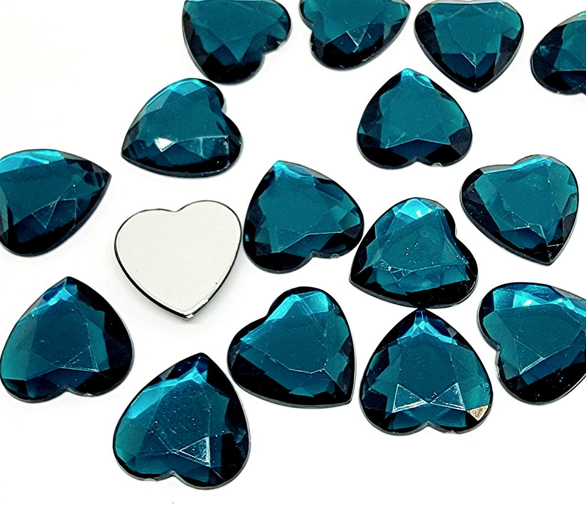Pile of 20mm faceted teal resin heart gem cabochons (cabs), one flipped to show the flat back