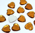 Pile of 20mm faceted topaz resin heart gem cabochons (cabs), one flipped to show the flat back
