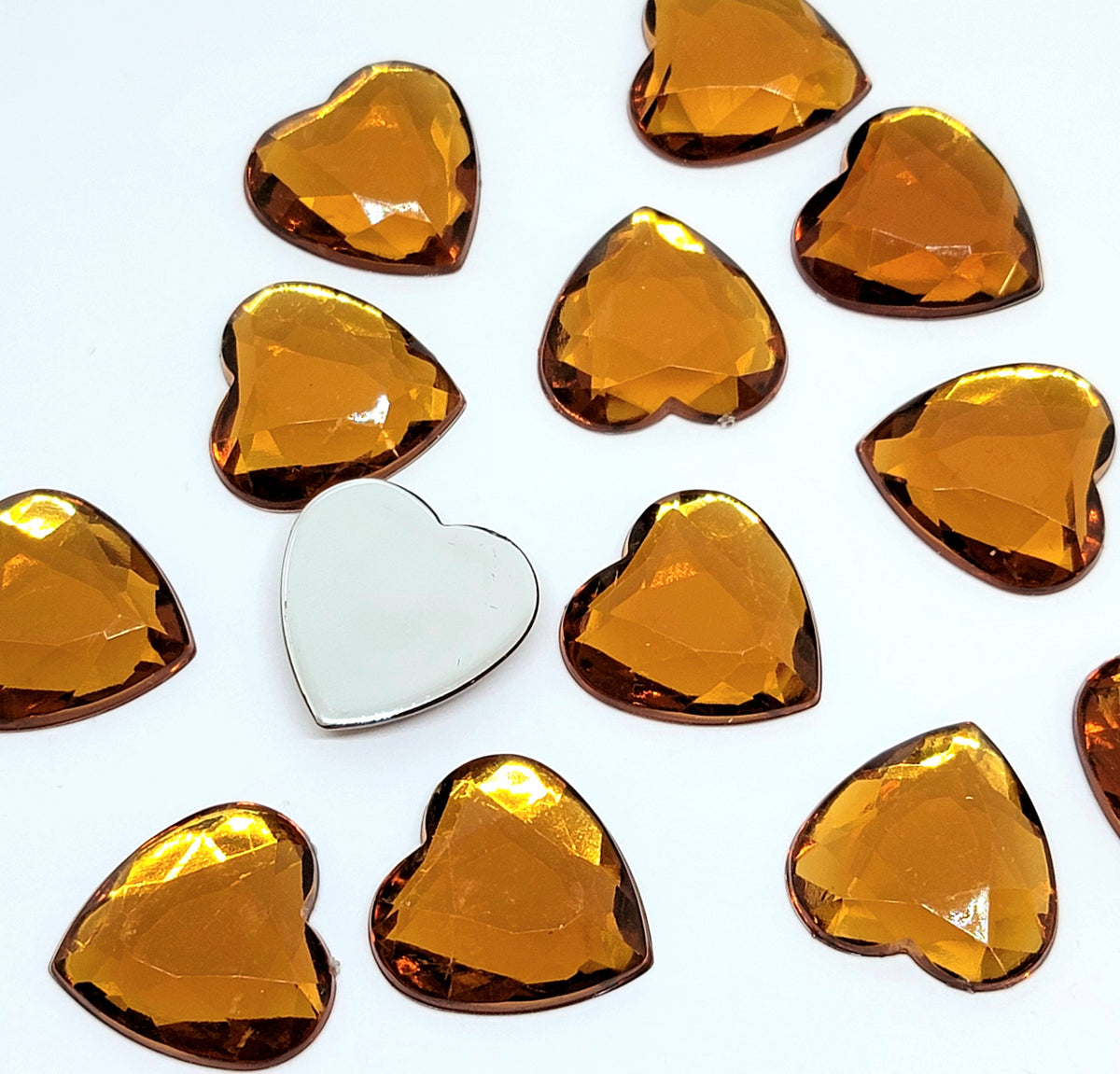 Pile of 20mm faceted topaz resin heart gem cabochons (cabs), one flipped to show the flat back