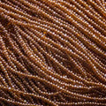 Close-up of strung Preciosa 13/0 true cut charlotte beads in transparent dark topaz with a luster finish