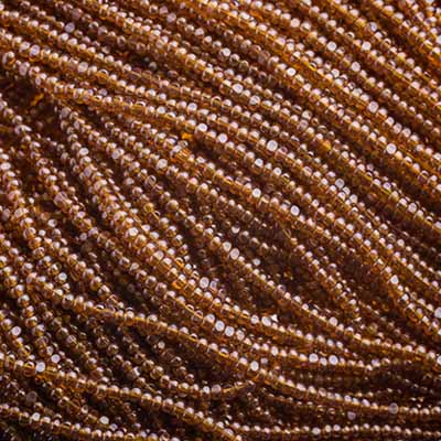 Close-up of strung Preciosa 13/0 true cut charlotte beads in transparent dark topaz with a luster finish