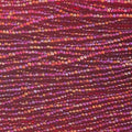 Close-up of strung Preciosa 13/0 true cut charlotte beads in transparent red with an AB rainbow finish