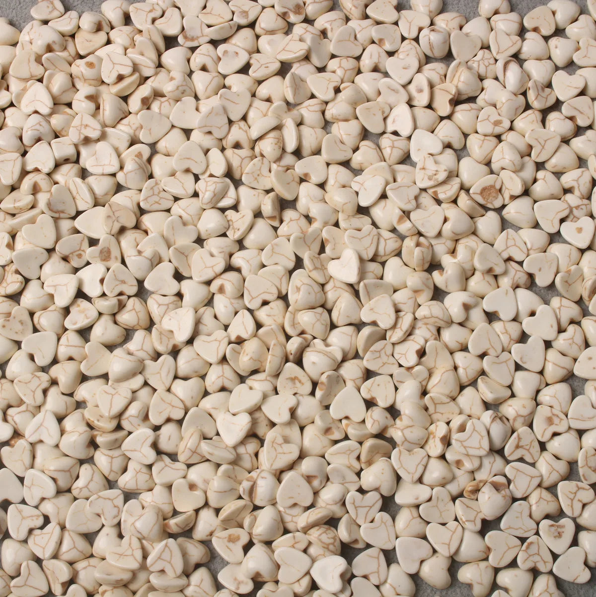 Pile of 10 x 14mm dyed howlite white heart cabochons (cabs) with natural veining