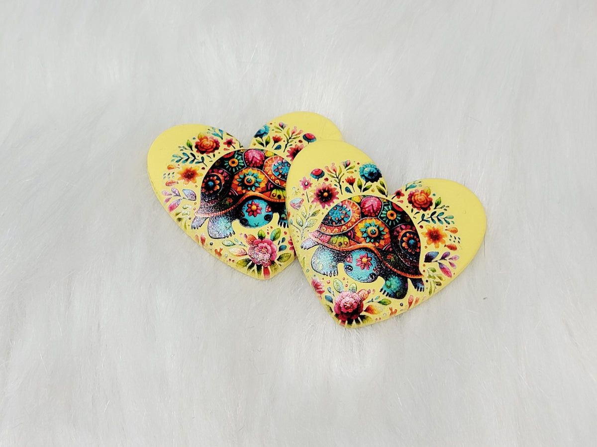 Pair of 37mm resin heart cabochons (cabs) in yellow with a patterned turtle among bright flowers