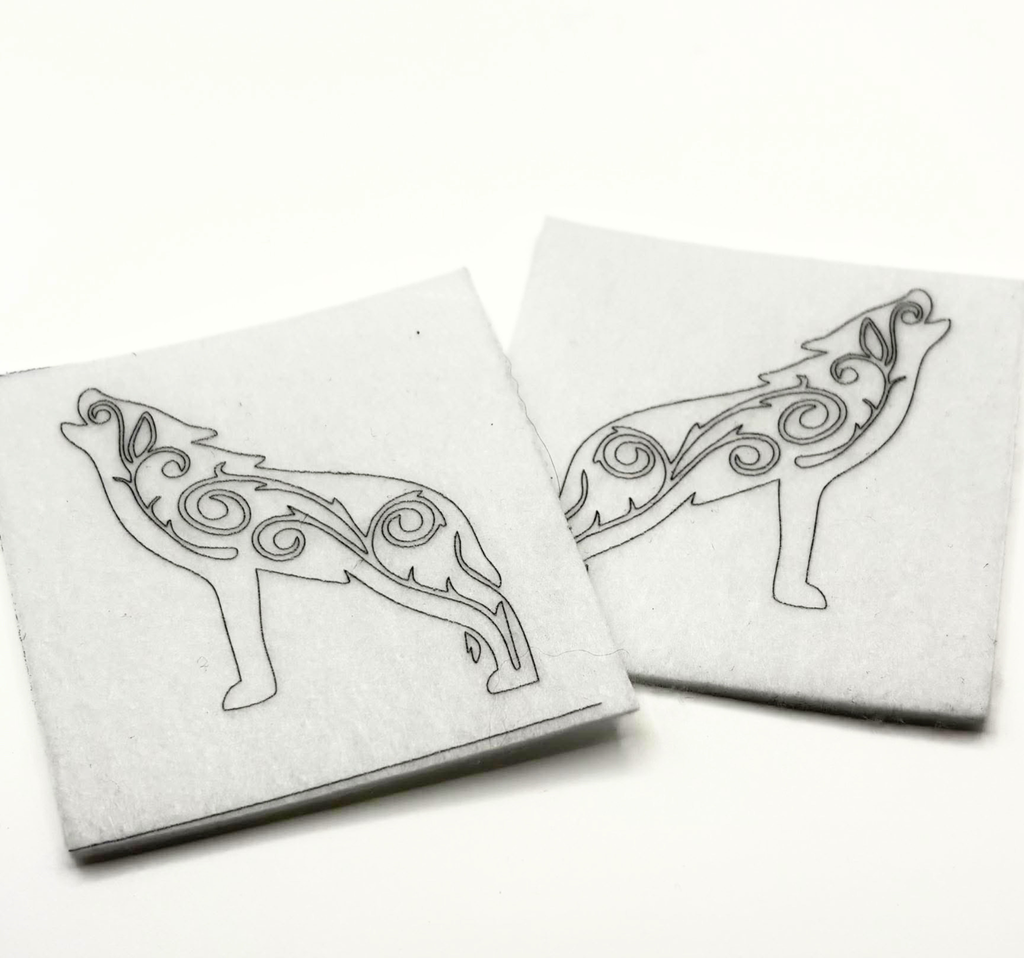 Two beading patterns printed in black on stiff white pellon squares, showing a howling wolf with swirls