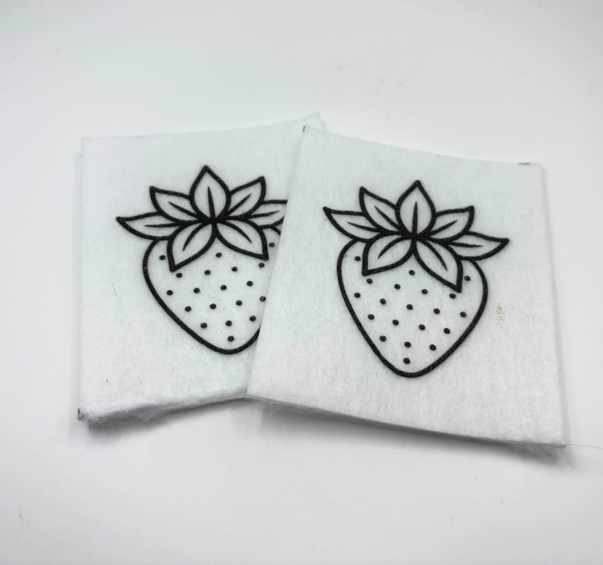 Two beading patterns printed in black on stiff white pellon squares, showing a strawberry
