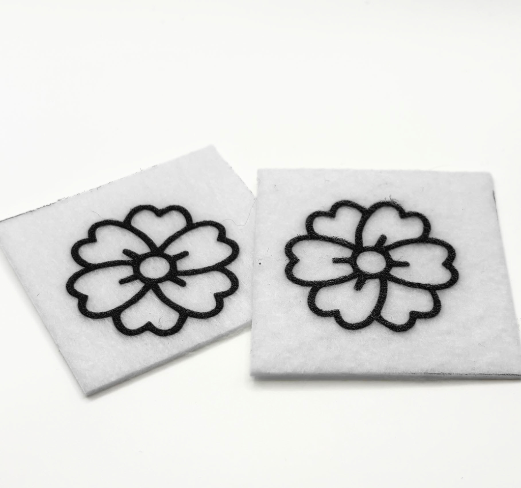Two beading patterns printed in black on stiff white pellon squares, showing a flower with notched petals