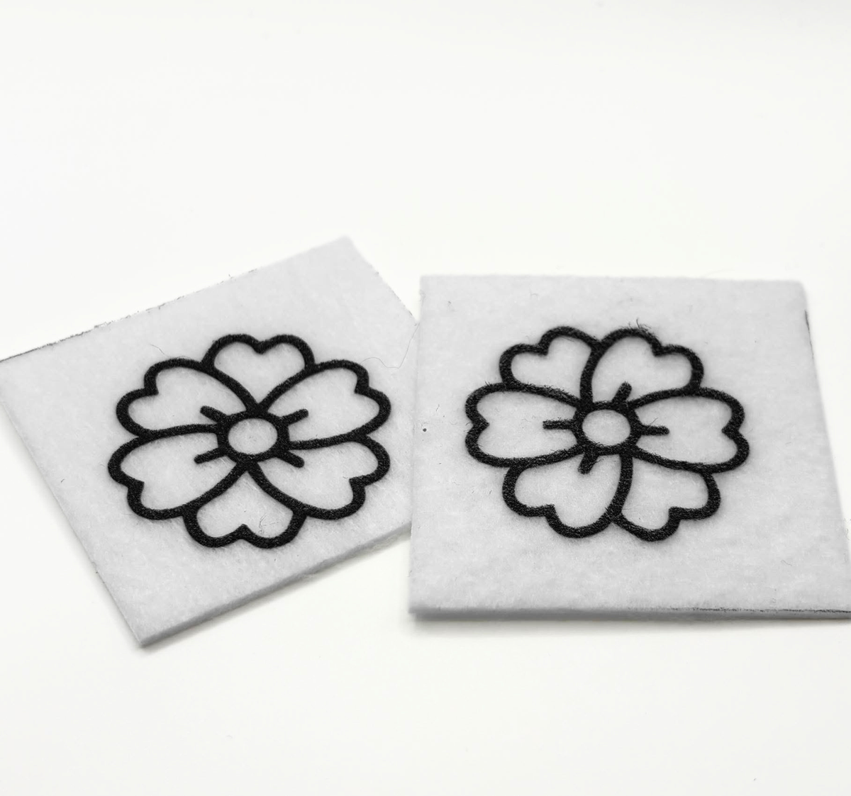 Two beading patterns printed in black on stiff white pellon squares, showing a flower with notched petals