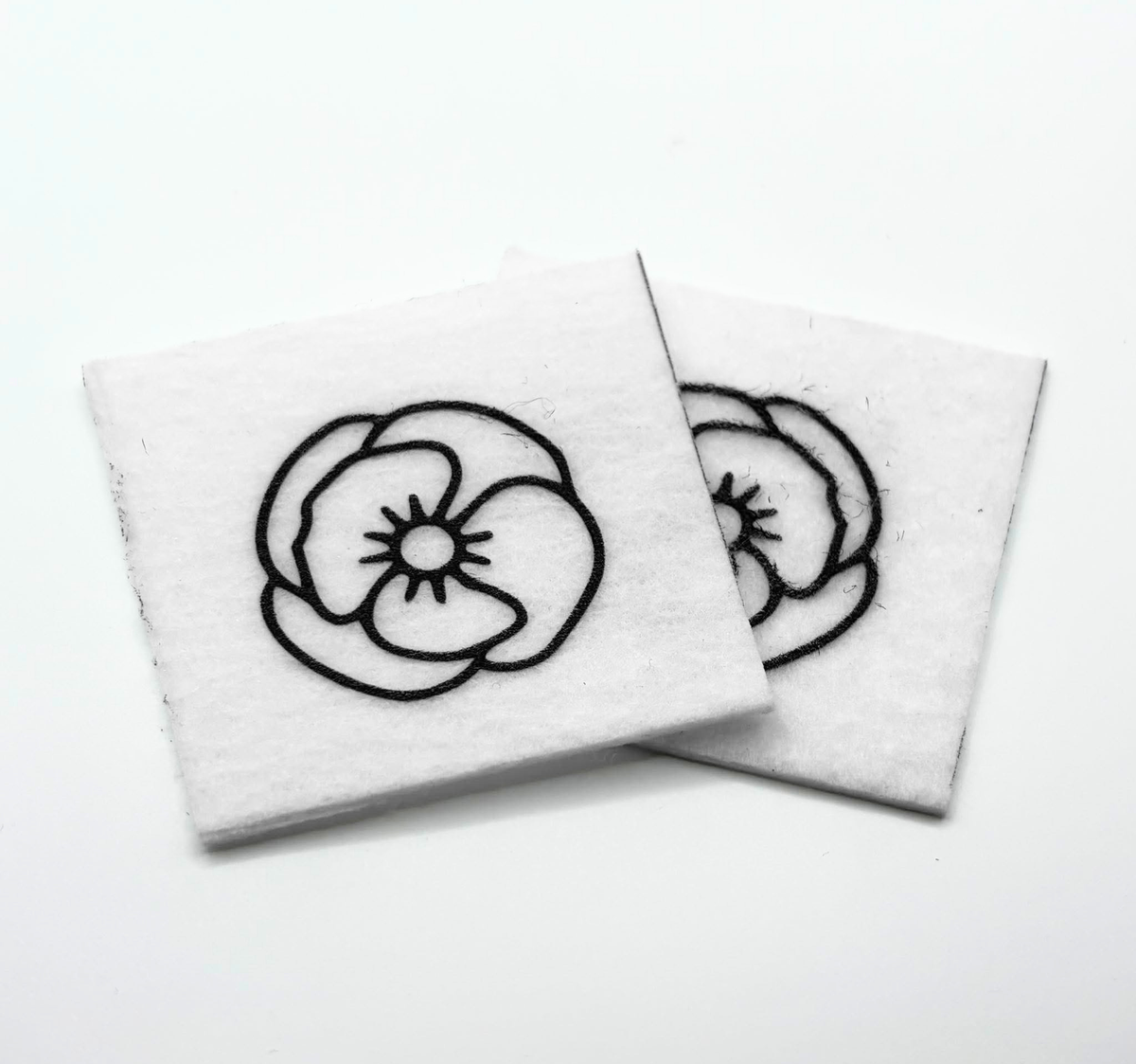 Two beading patterns printed in black on stiff white pellon squares, showing a pansy-style flower
