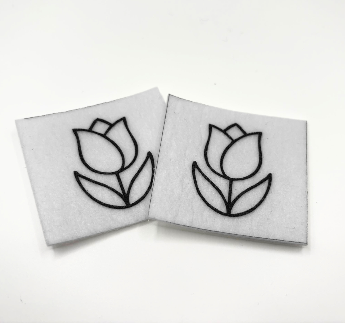 Two beading patterns printed in black on stiff white pellon squares, showing a tulip
