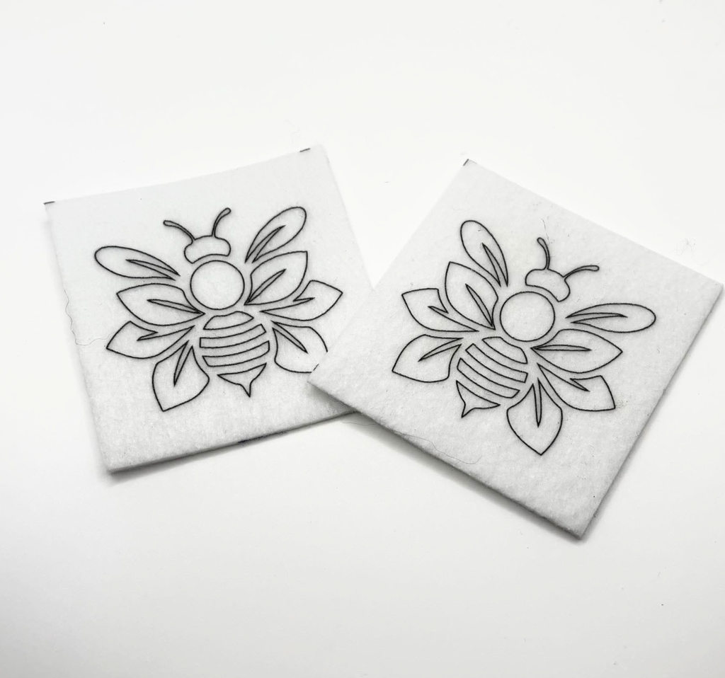 Two beading patterns printed in black on stiff white pellon squares, showing a outlined bee with layered wings