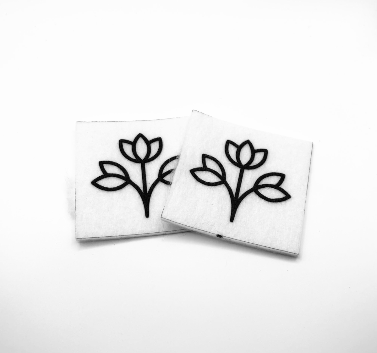 Two beading patterns printed in black on stiff white pellon squares, showing a three-bud flower sprig