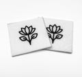 Two beading patterns printed in black on stiff white pellon squares, showing a lotus-style flower with leaves