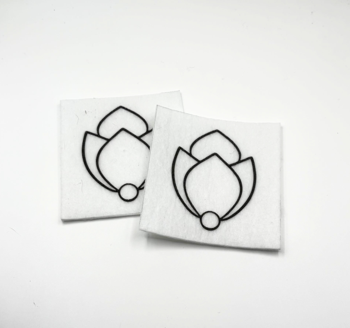 Two beading patterns printed in black on stiff white pellon squares, showing a tulip bud with a pearl
