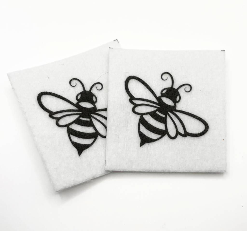 Two beading patterns printed in black on stiff white pellon squares, showing a flying bee